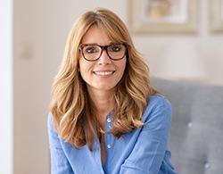 Woman with glasses sitting on couch and smiling