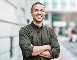 Man in button-up shirt smiling with arms folded