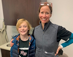 Smiling woman and boy standing together in a casual indoor setting.