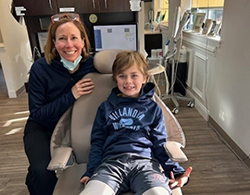 A woman and a boy smile while sitting in a dental office